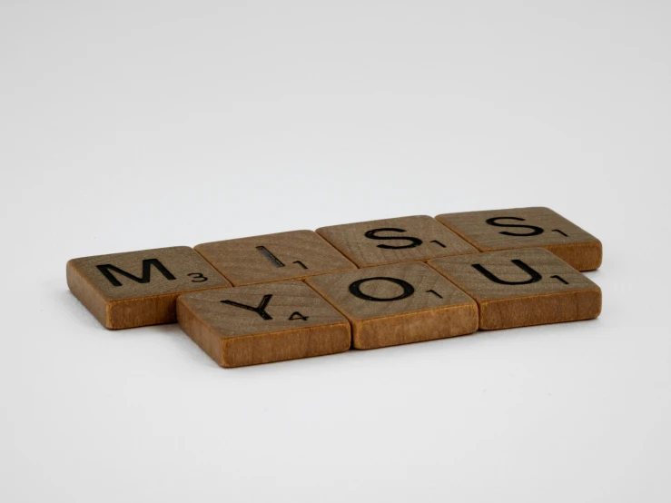 three wooden blocks spelling out the word miss and miss you