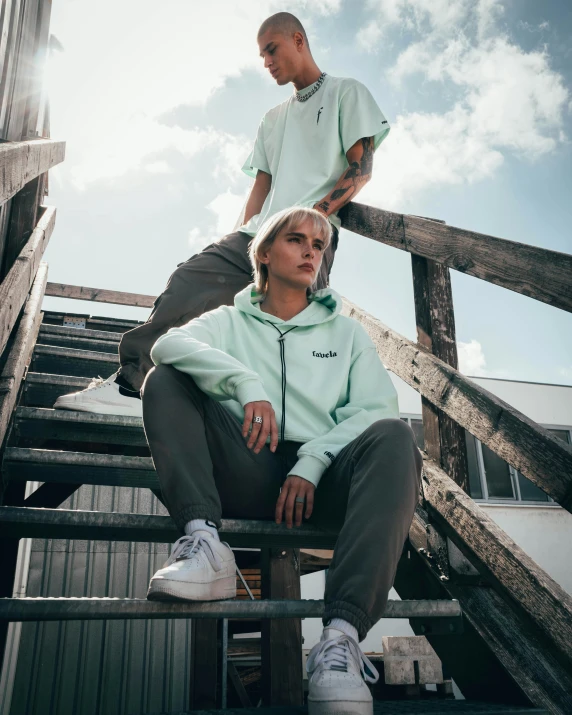 a couple of young people sitting on top of a wooden set of stairs