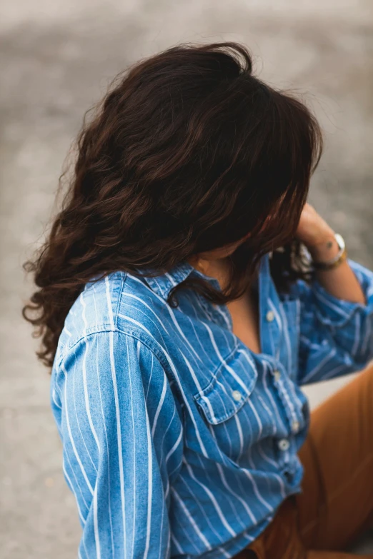 a girl is sitting on the concrete talking on a phone