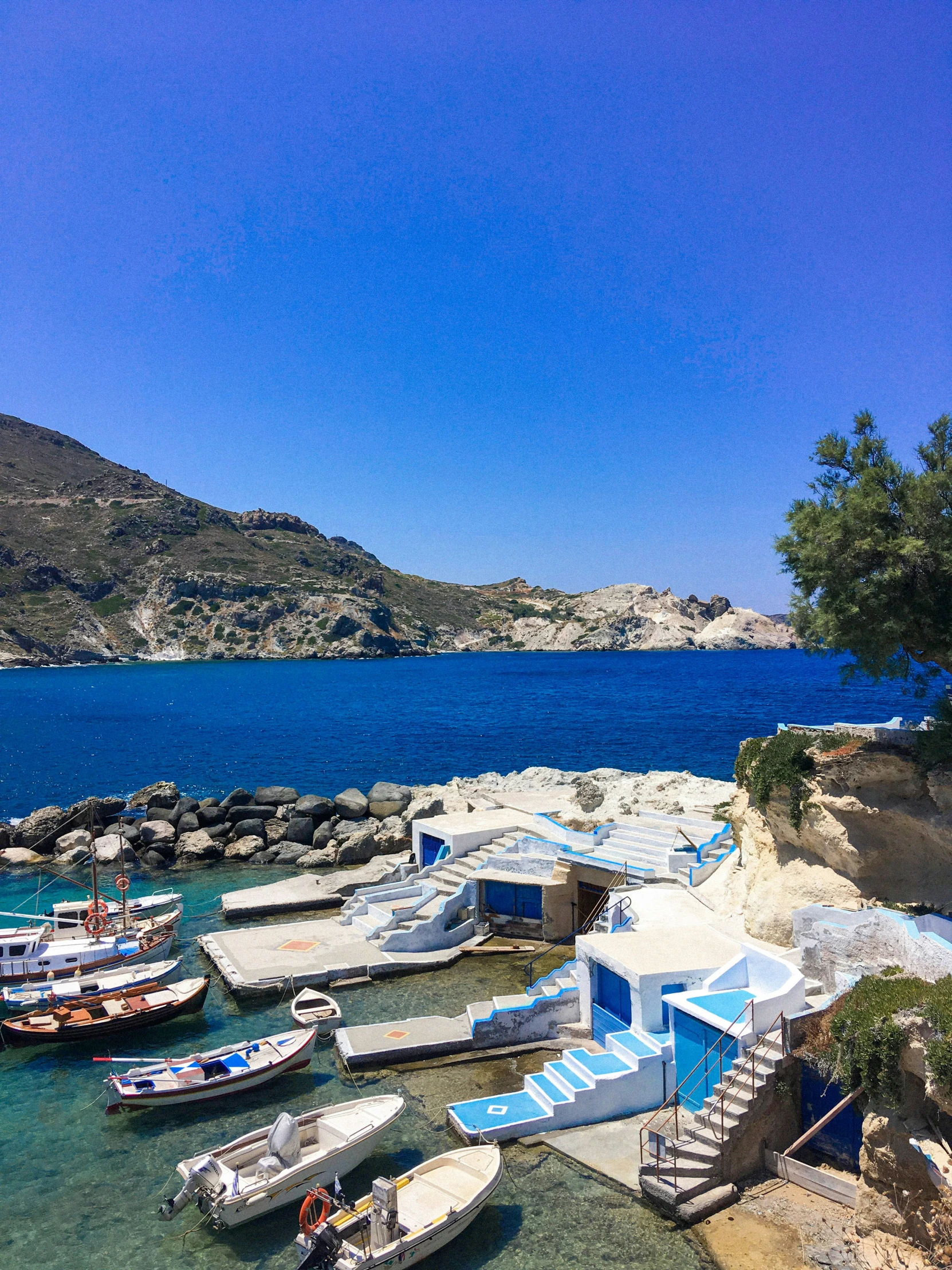 several small boats tied to a pier near the ocean