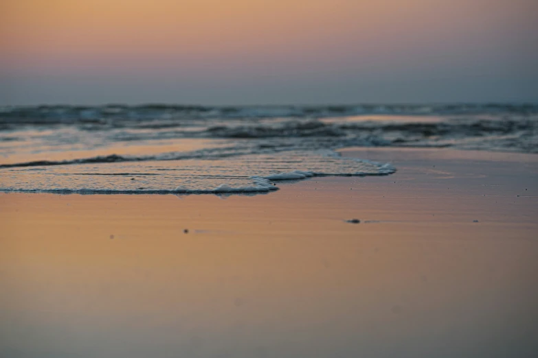 a sunset and sand area with a small wave