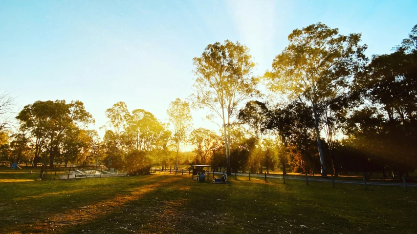 the sun is setting in the distance behind some trees