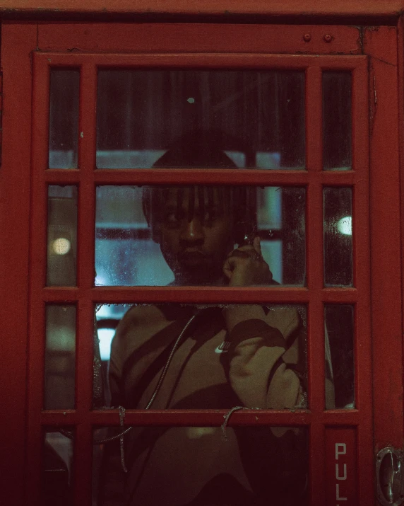 a woman talking on a cell phone with a red telephone booth