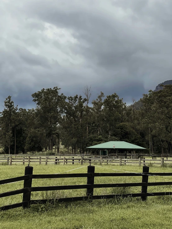 an open field with a black fence and green roof