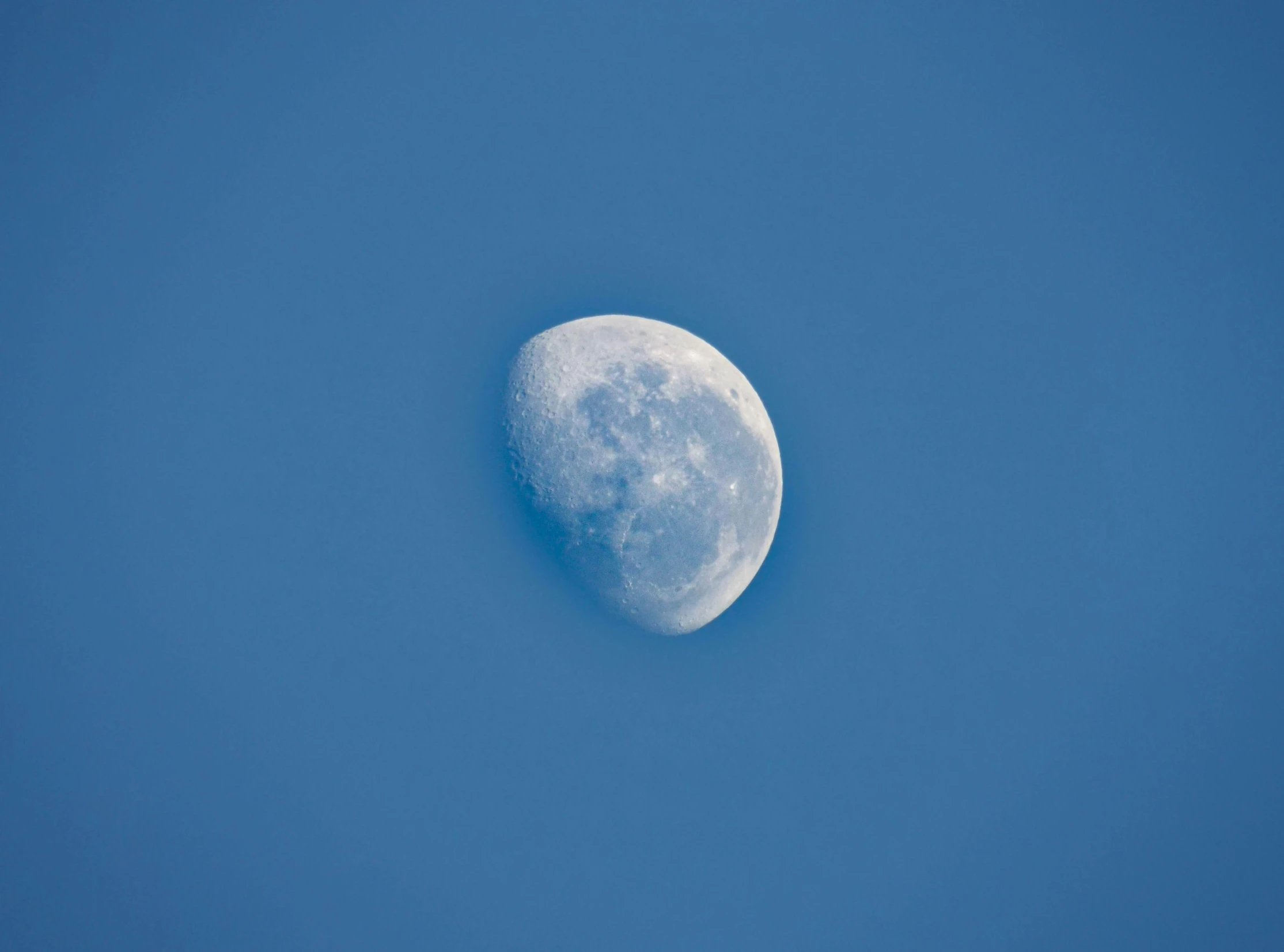 a half moon against a bright blue sky