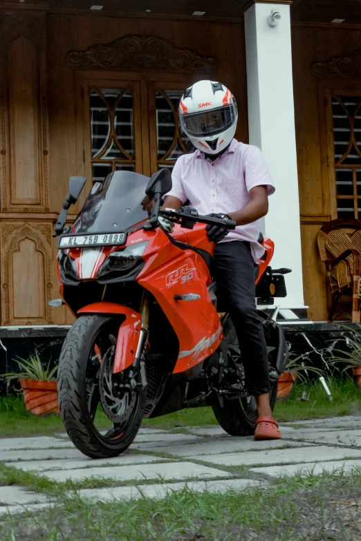 a man wearing a helmet sits on his red motorcycle