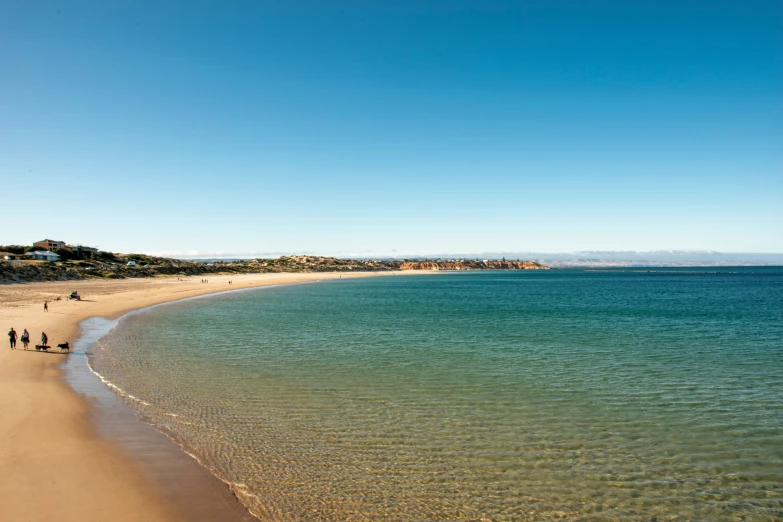 two people walking along the shore line to an ocean