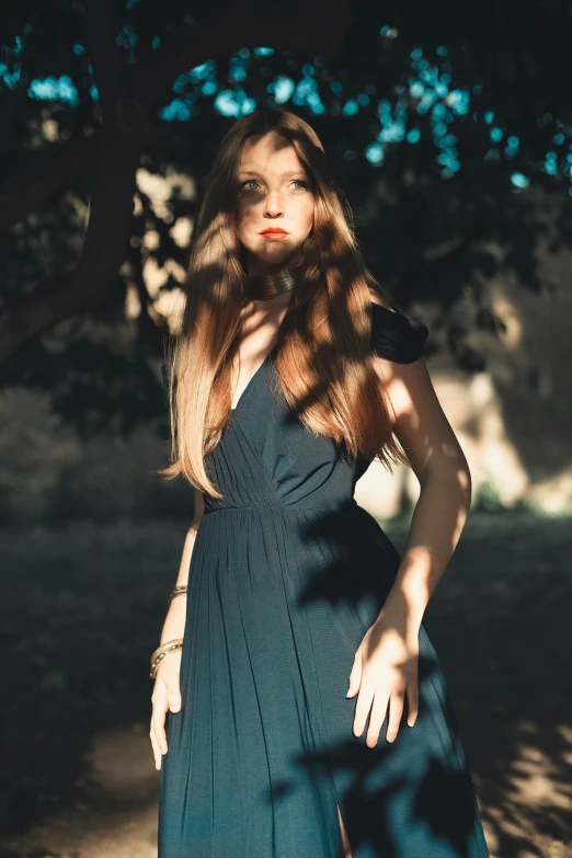 a woman with red lips stands near a tree