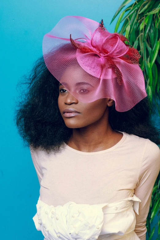 a black woman wearing a pink hat with a red bow