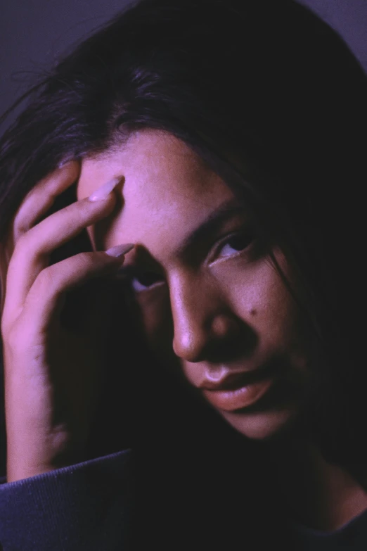 a young woman smiles while holding her hands to her head