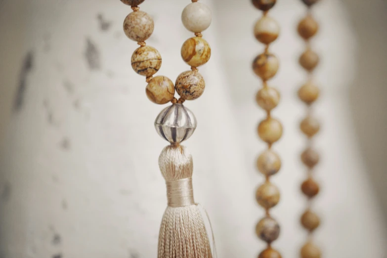 a beaded and tasselled necklace in front of a wall