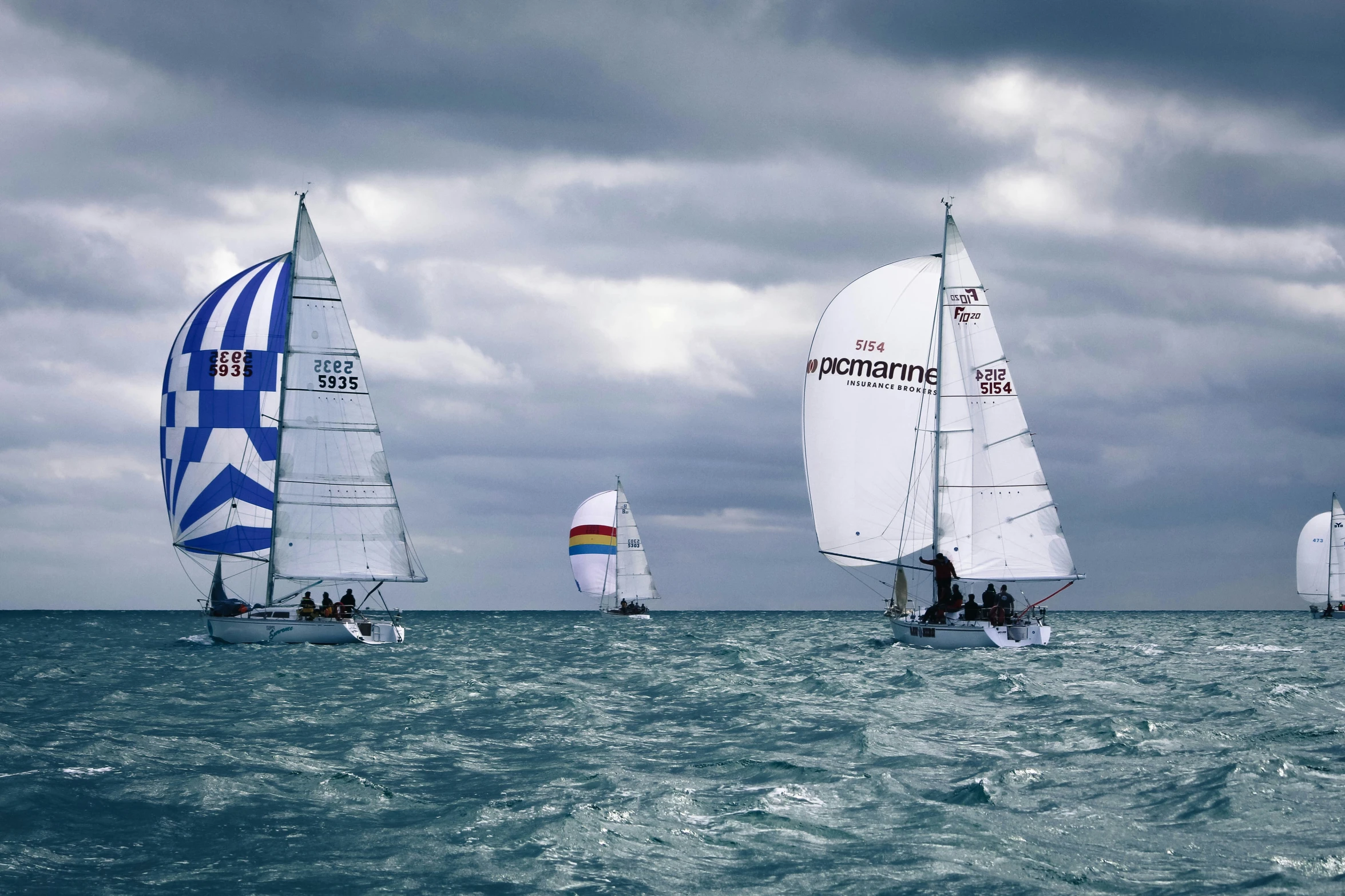 several sail boats are sailing through the ocean