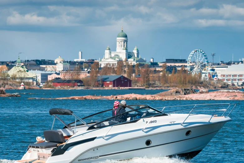 a boat going in the water with a city behind it