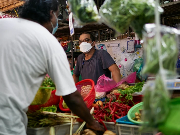 two people wearing masks are at a farmers market