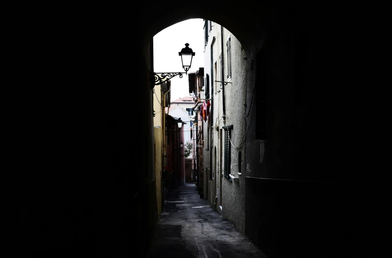 a narrow alley with a street light in the dark