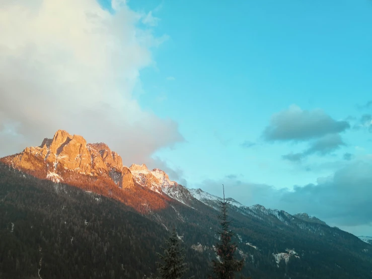 the sun breaks up behind a snowy mountain peak