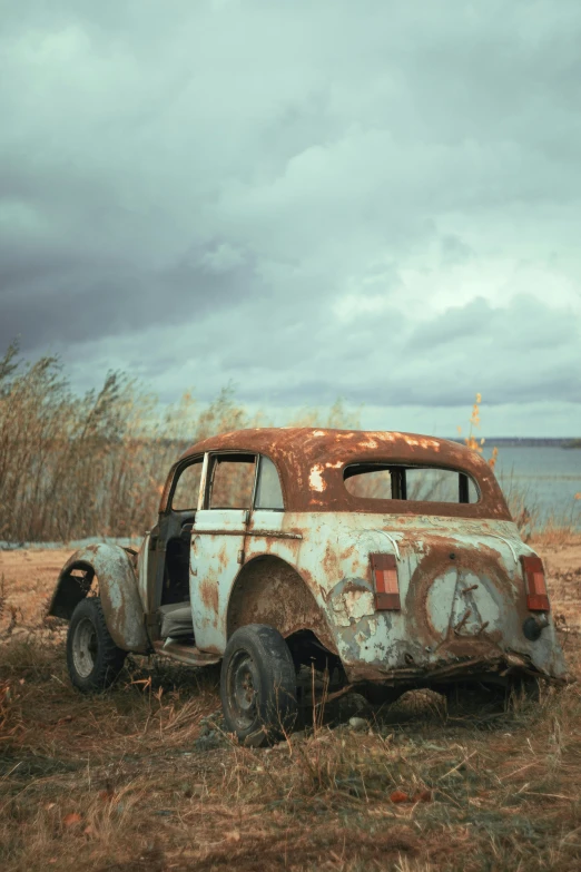 an old dirty truck is parked next to a body of water