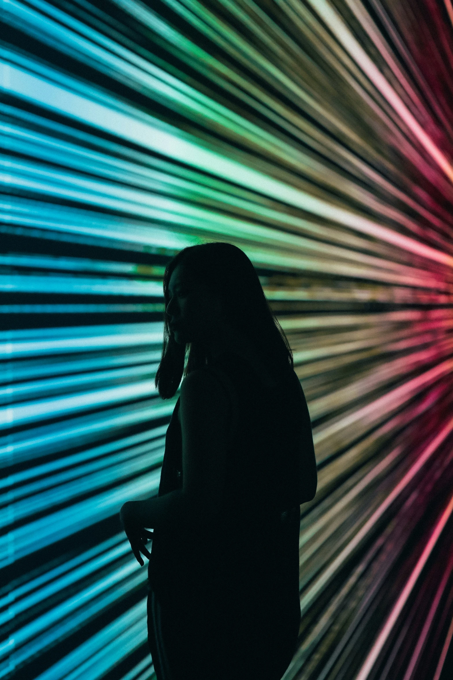 a person standing in front of an art exhibit with a rainbow - colored backdrop