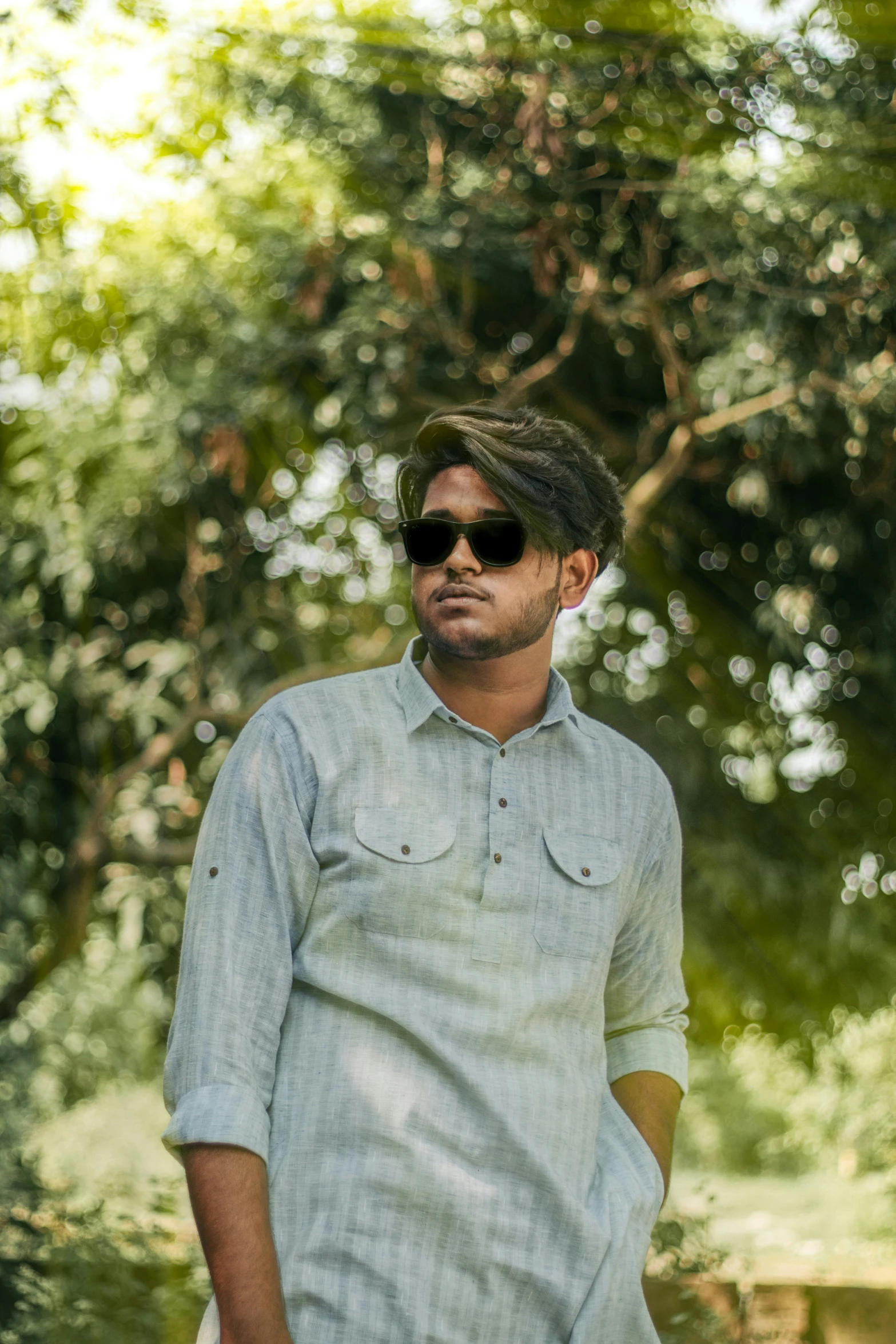 a man in sunglasses and a shirt standing outside