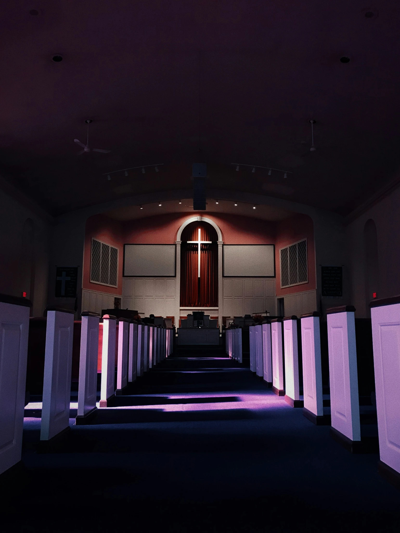 the long hallway with two rows of stalls leading up to the cross