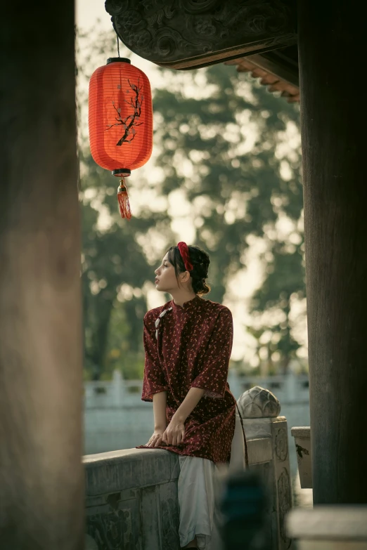 a woman sitting down next to an orange lantern