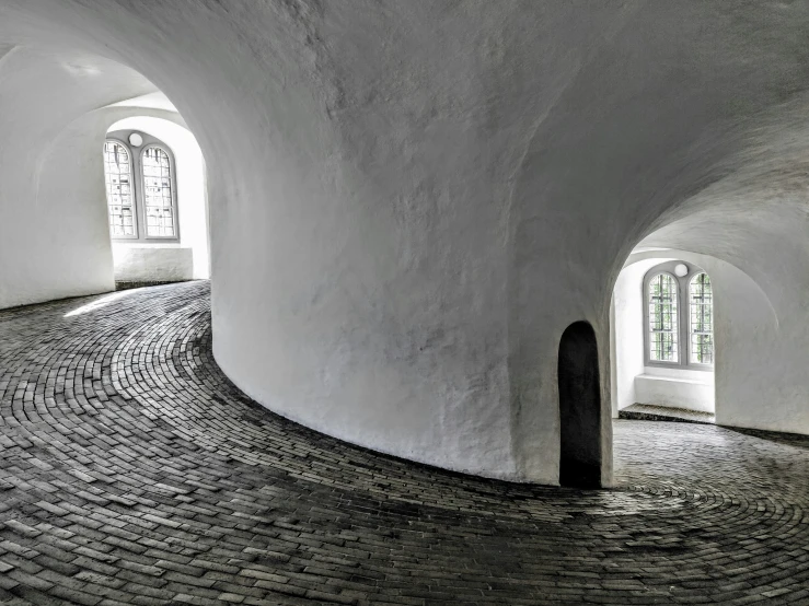 a room with three windows and brick floor