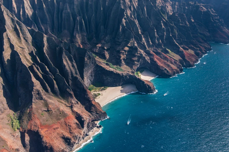 a small group of boats on the water near a mountain