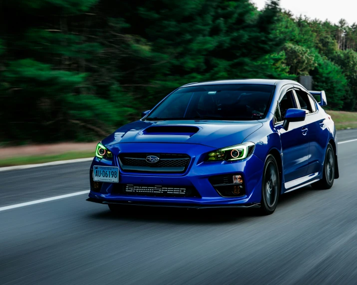 a blue subarunt driving on the road near trees