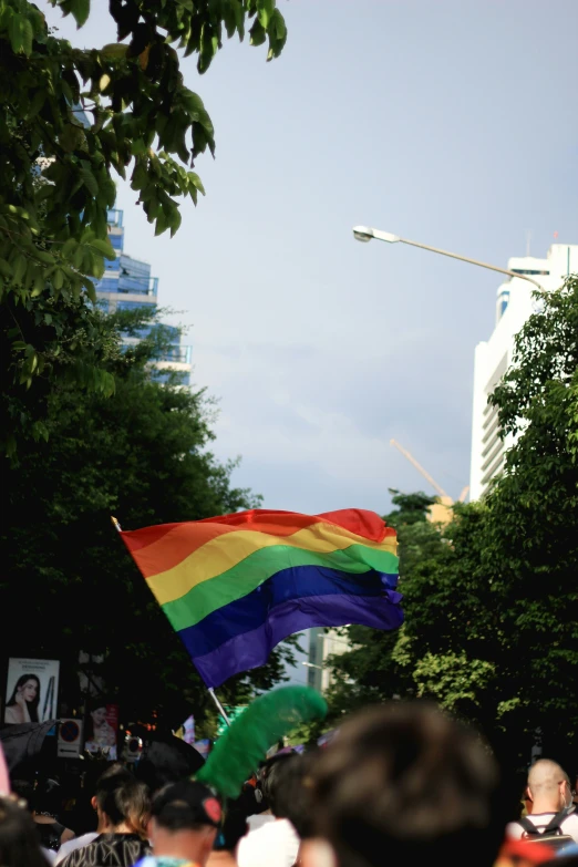 a rainbow flag with people holding umbrellas on the sides of the street