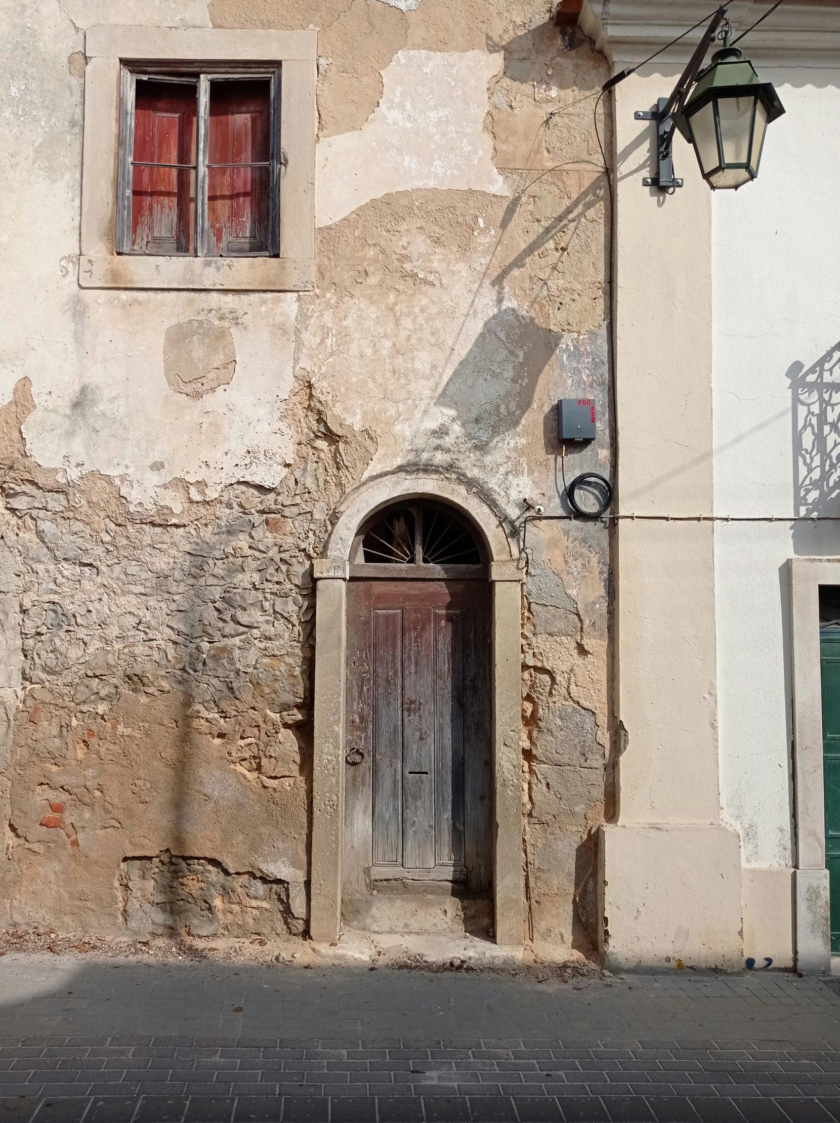 an old, bricked wall and two large doors on a city street