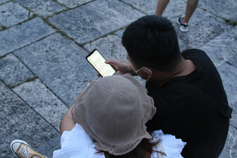 two people sitting together using their cell phones