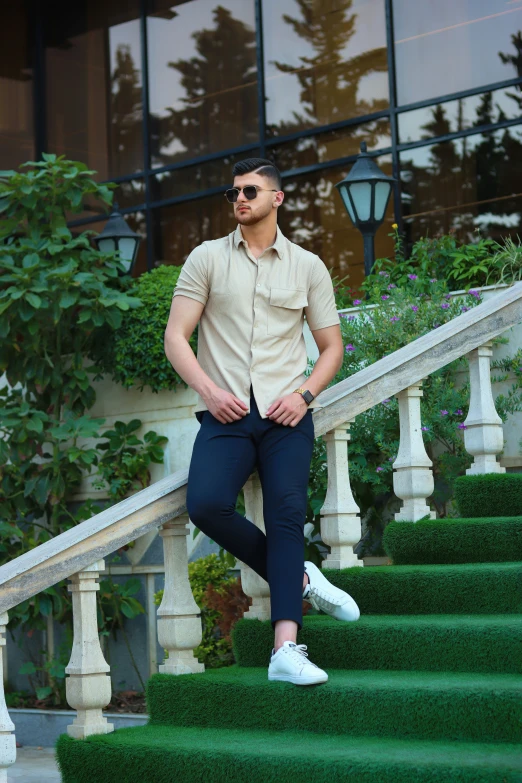 a young man is posing on the stairs of a building
