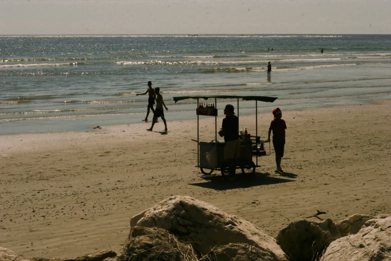 a man walking on the beach with two people behind him