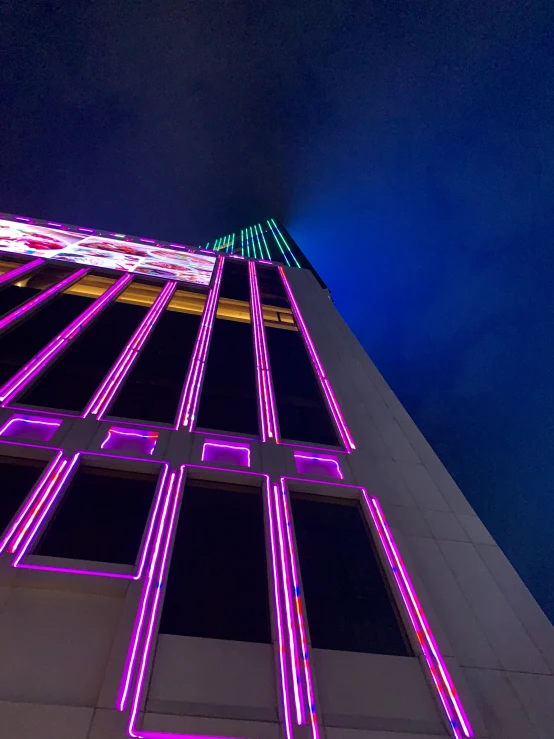 a large tall building with neon lights on it's side