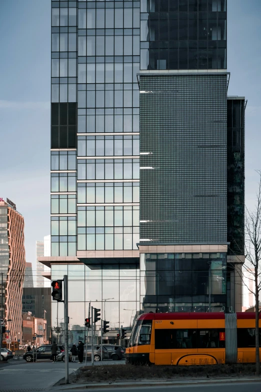 a yellow bus on a city street in front of a large building