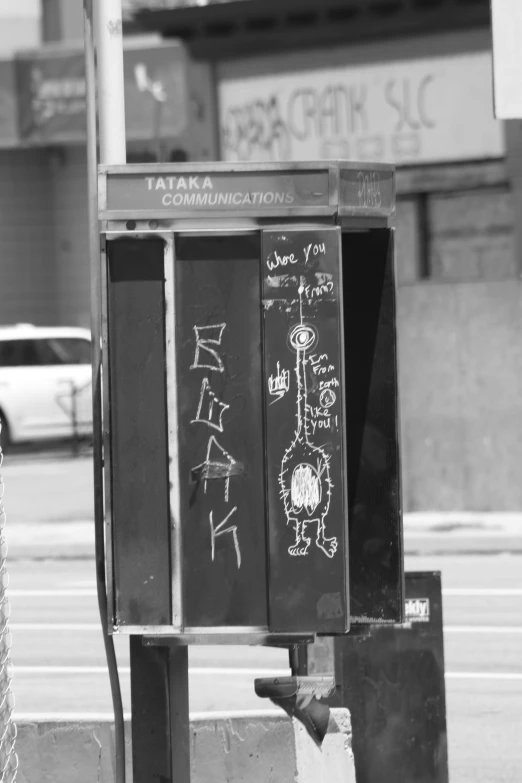 the public phone has been graffitied on the sidewalk