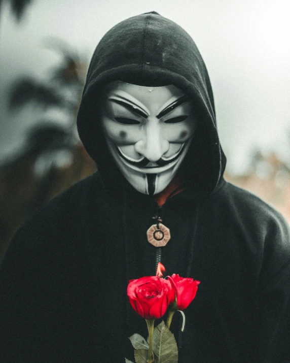 a man in a scary mask holding a red rose
