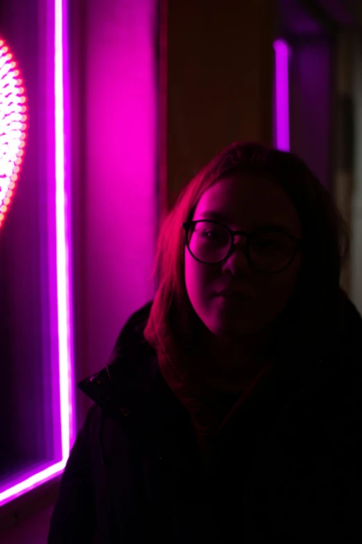 a woman wearing glasses in front of a purple light