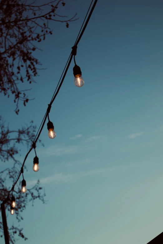 the lights of street lamps hang from an old electrical line