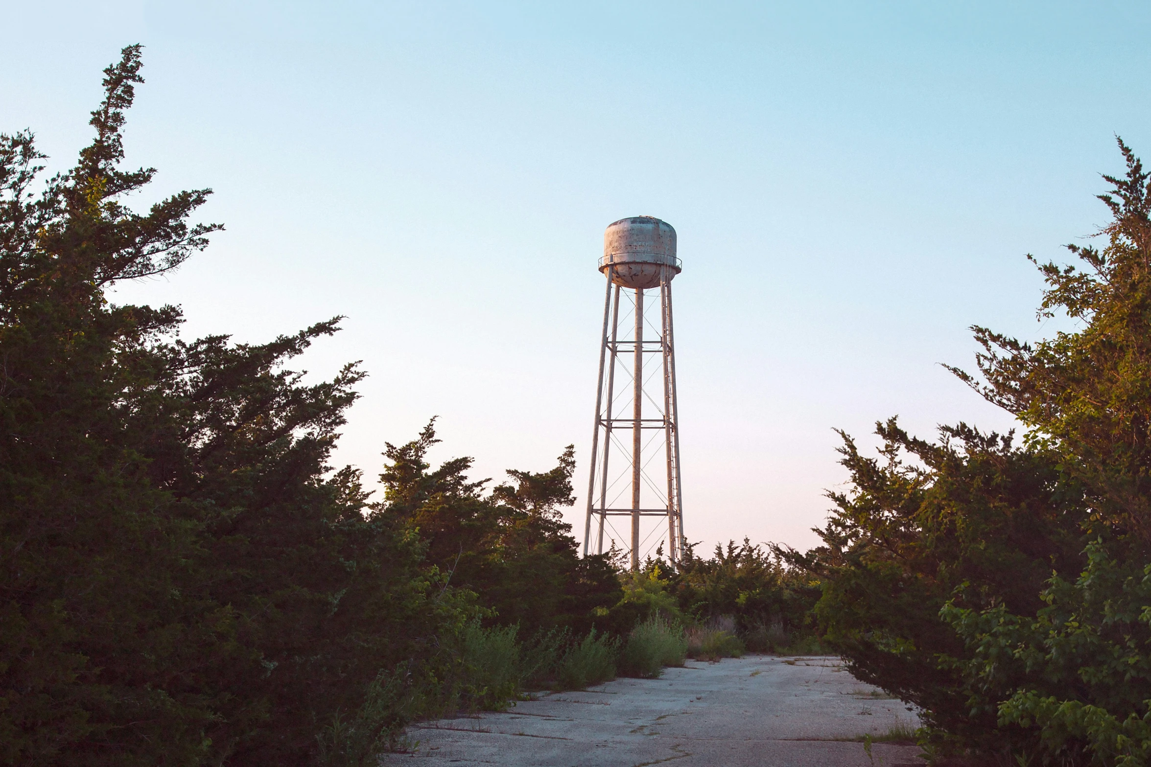 a small white water tower near many trees