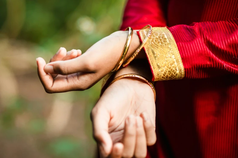 woman holding a mans hand with her arm wrapped in gold fabric