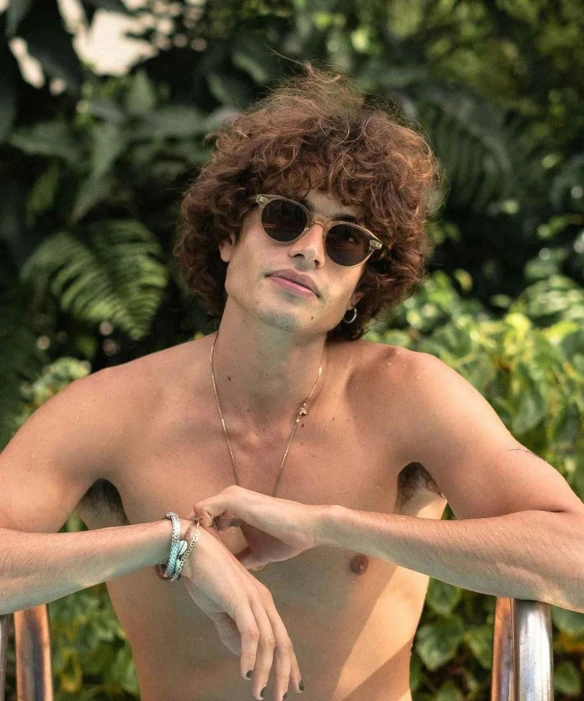 man with sun glasses standing next to some plants