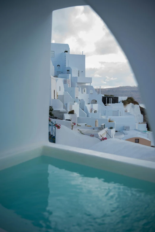 a small pool surrounded by white buildings with water in it