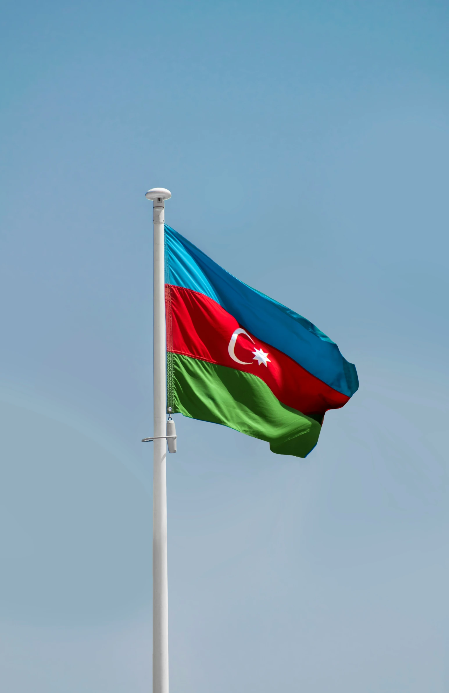 a flag waving against the blue sky