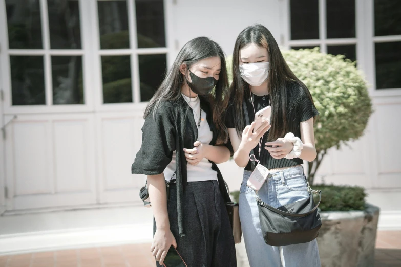 two women wearing masks are standing by a house