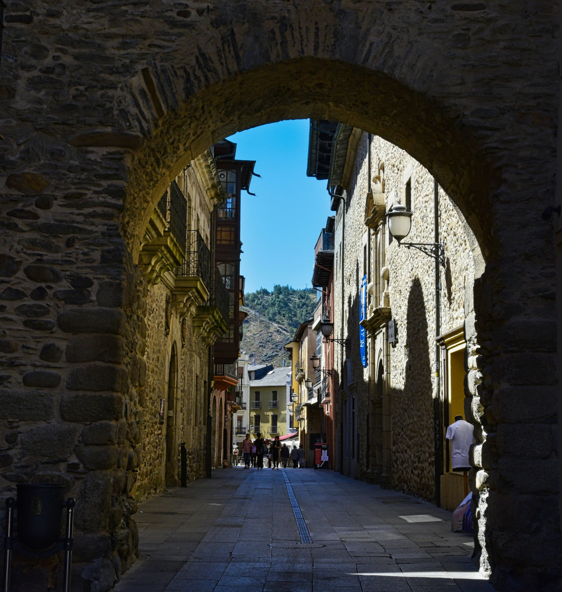 an archway is over the walkway and a cobblestone alley