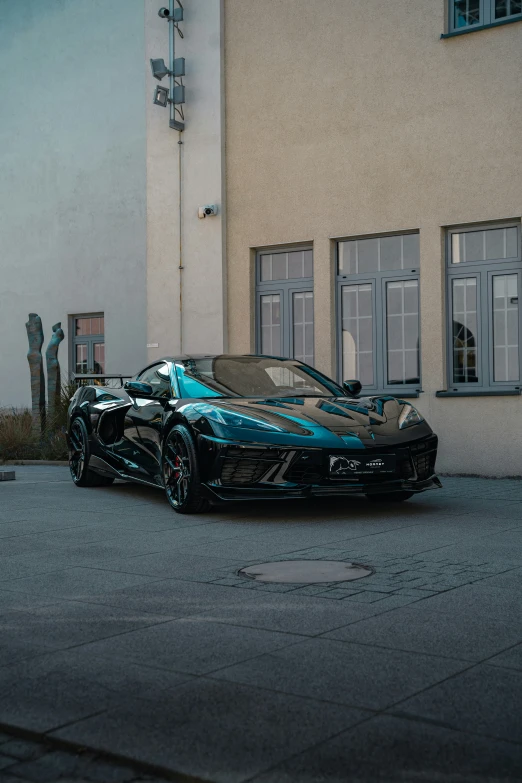 a black sports car with a blue front split sitting in front of a white building