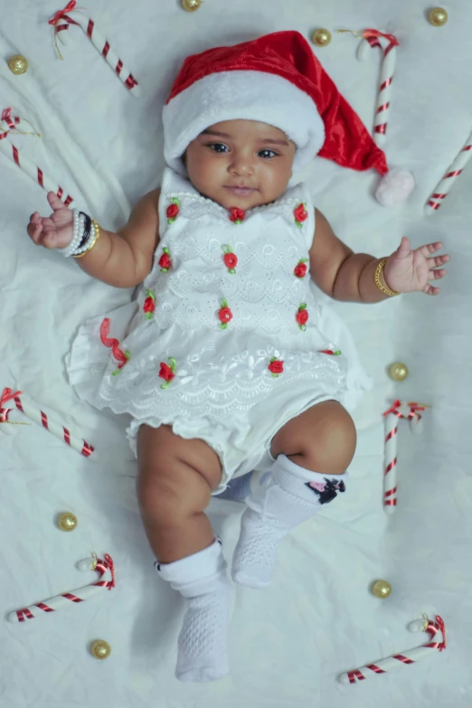 a baby laying on the ground wearing a christmas hat