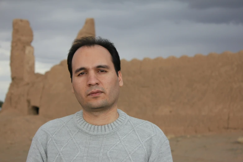 the man is posing for a picture in front of a sand castle