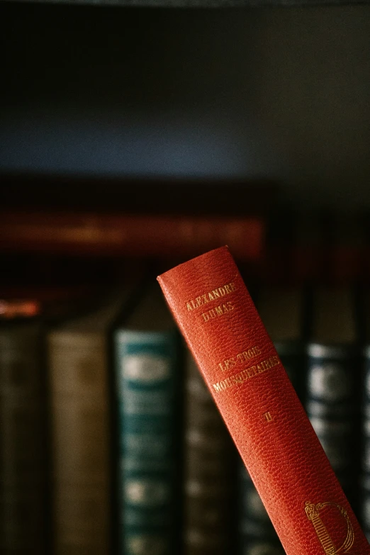 a red book standing up against some bookshelves